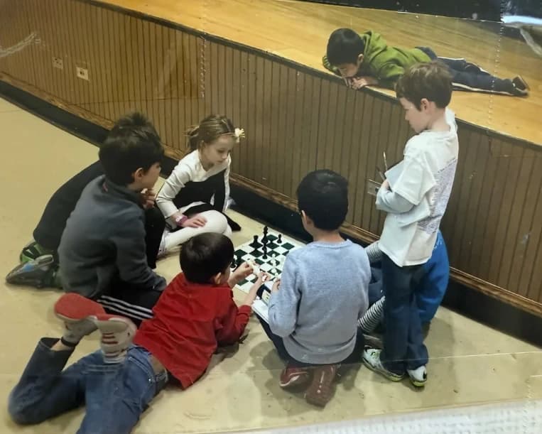 Sophia surrounded by boys at a chess tournament, playing a match