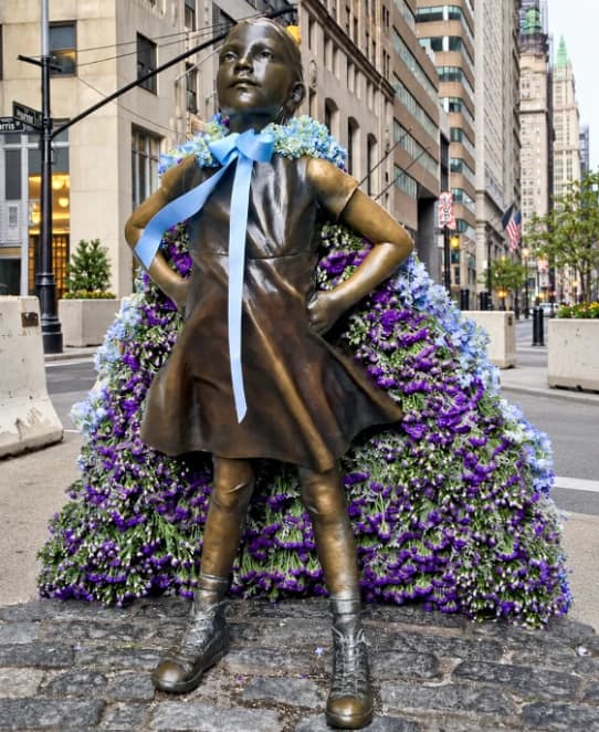 The Fearless Girl statue dressed in a gown of purple and blue flowers