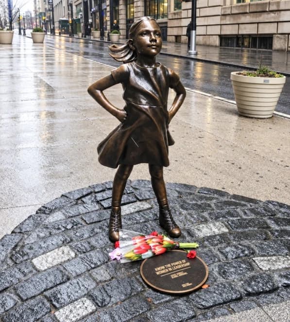 The Fearless Girl statue with flowers left at her base