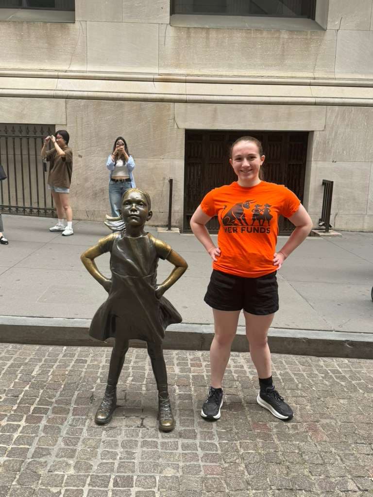 Sophia DeGregorio in a Her Funds t-shirt next to the Fearless Girl statue