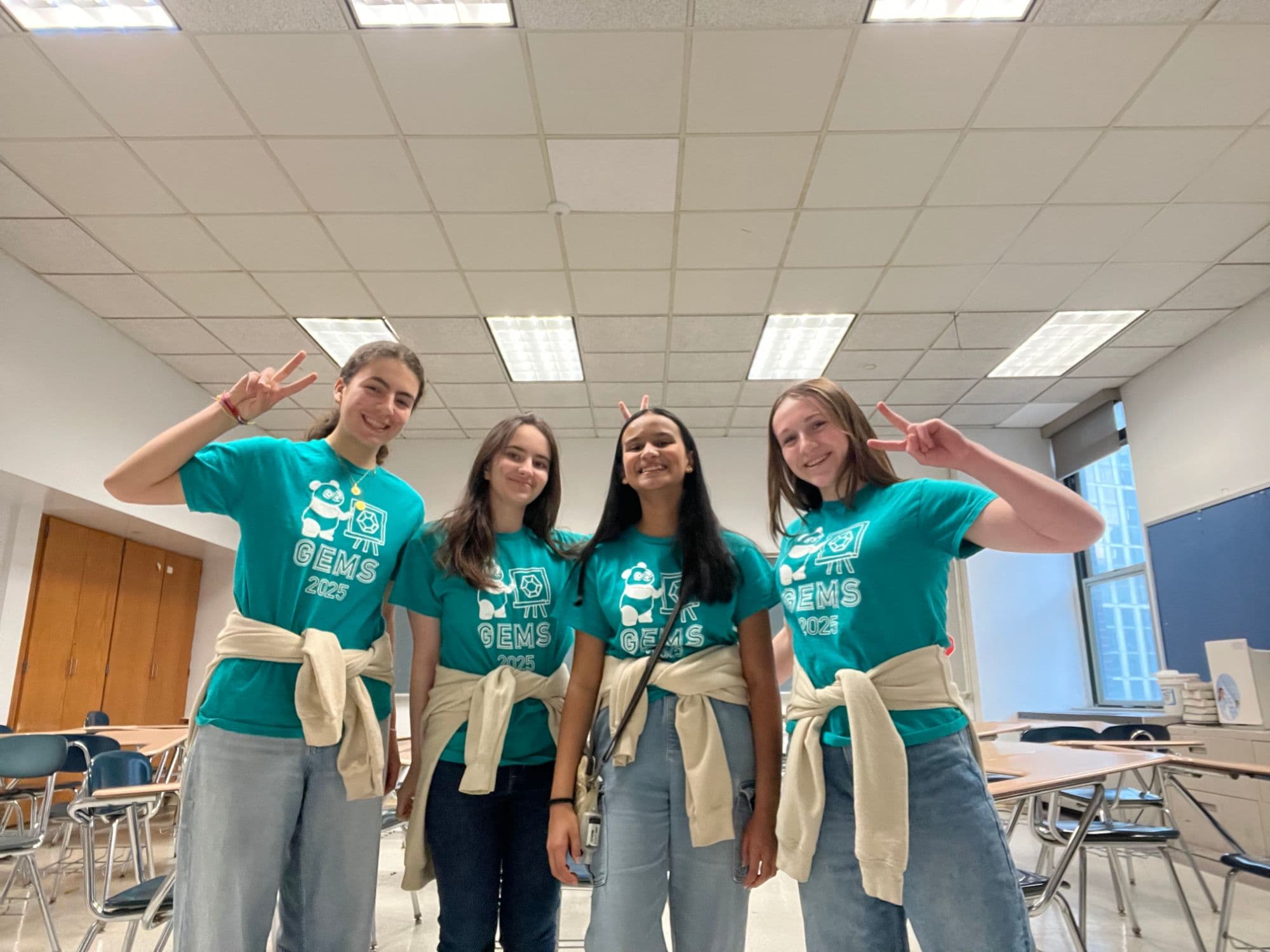 Four GEMS 2025 team members posing together in a classroom