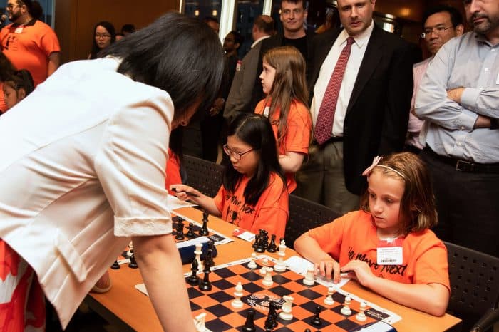 Hou Yifan playing a simul game against a young Sophia DeGregorio at a chess tournament